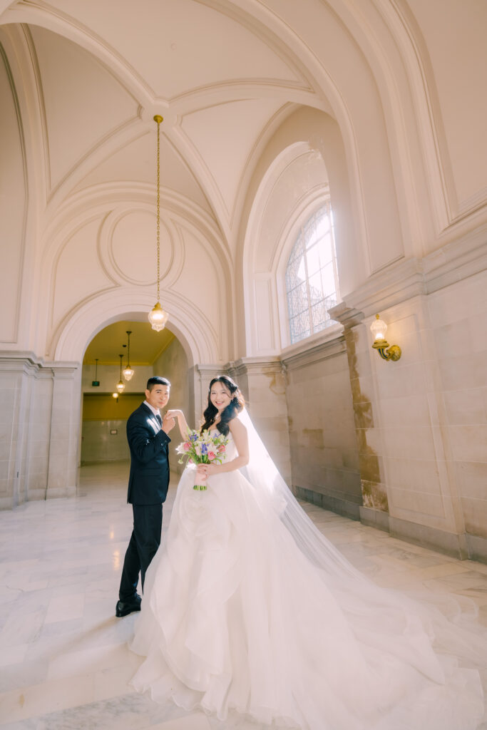 Anh and Tuan holding hands beneath the vaulted corridor arches