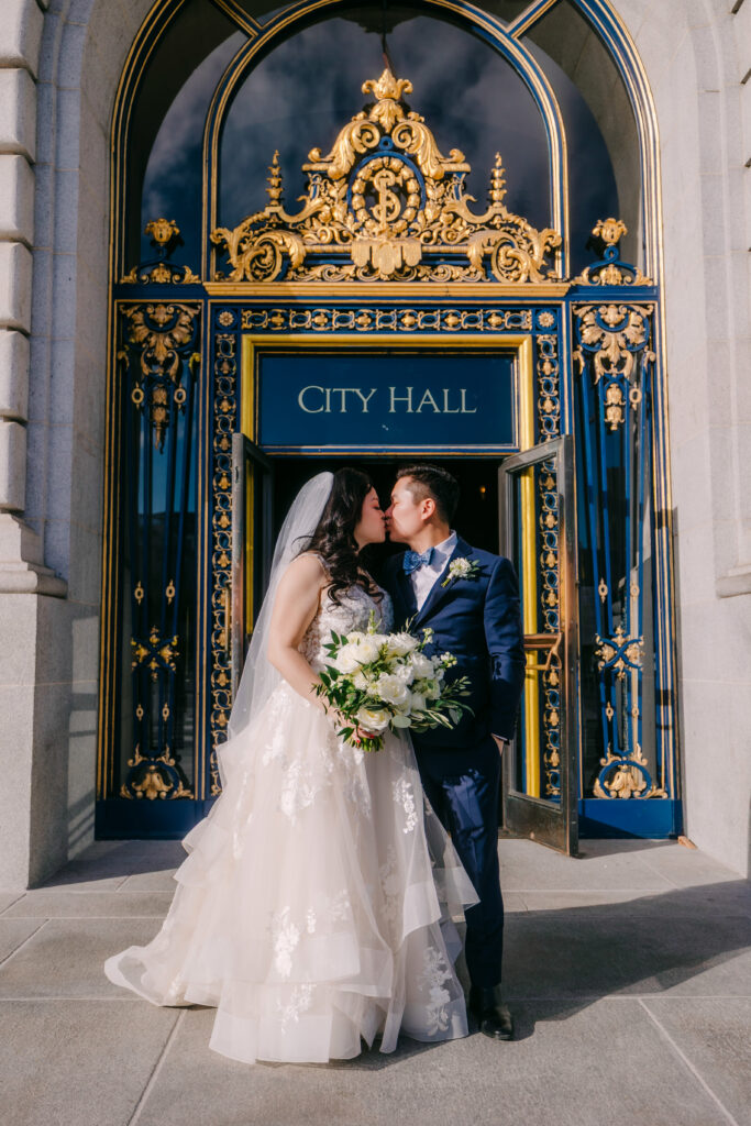 Casey and Minh kissing in front of the City Hall doors