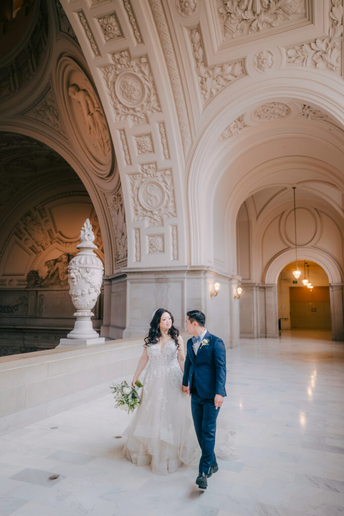 Casey and Minh walking hand in hand through an ornate hallway