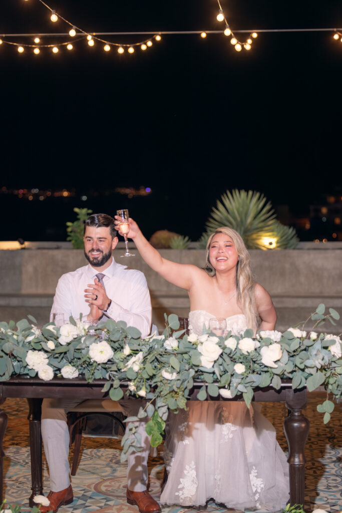 Jennifer raising a champagne toast at an outdoor reception table
