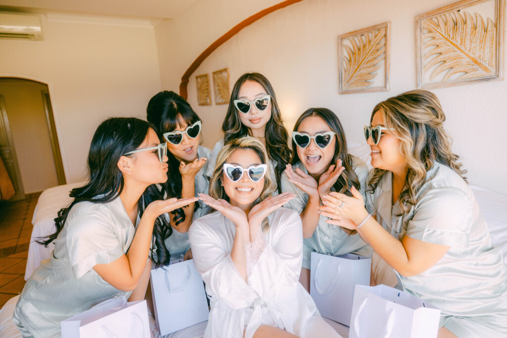 Jennifer and her bridesmaids laughing in heart-shaped sunglasses