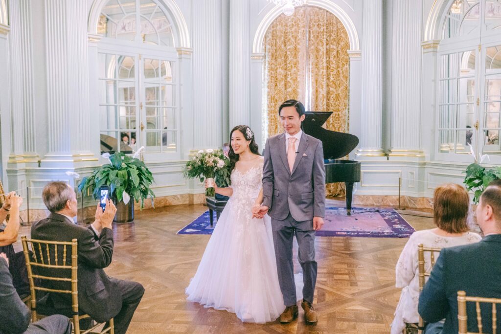 Monica and Kevin walking hand in hand through Filoli ballroom after their ceremony