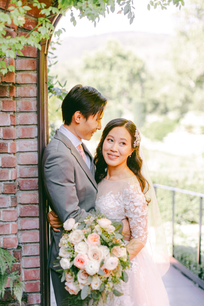 Monica and Kevin embracing beneath a brick arch at Filoli